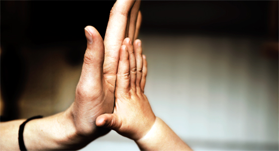 Närbild på vuxen och barns händer som gör high five.
