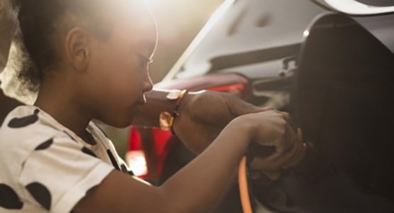 Flicka laddar elbil.