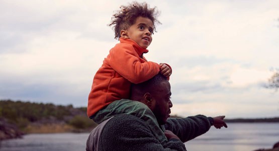 Pojke sitter på sin pappas axlar.