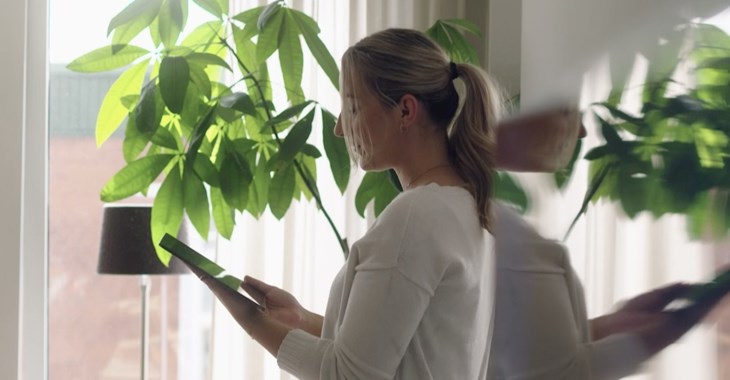 Kvinna som arbetar vid datorn i ett ljust hem.