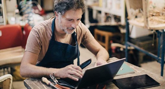 Man som sitter i verkstad och jobbar vid en laptop.