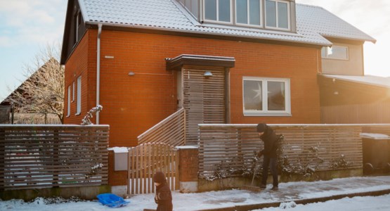 Pappa och barn utanför villa, vintertid.