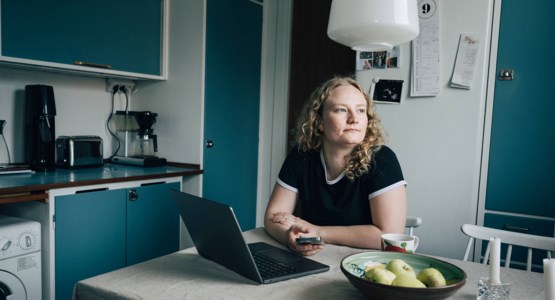 ung tjej sitter vid sin dator i köket