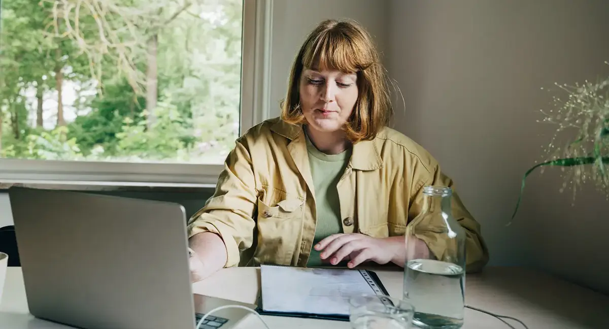 Kvinna ser över sin amortering framför dator.