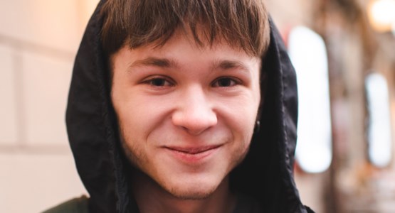 Tonårskille i luvtröja, ser glad ut.