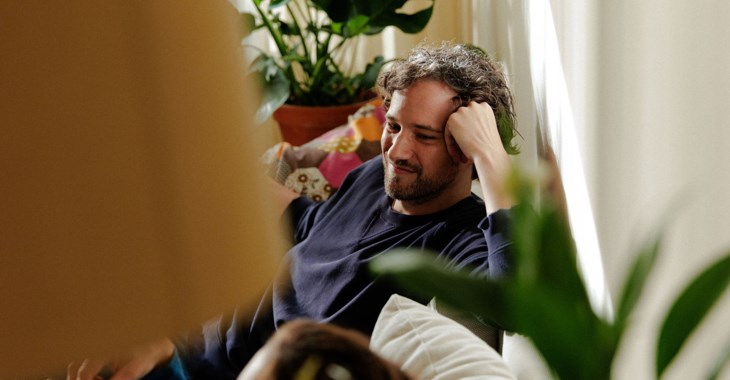 En man sitter i en soffa.