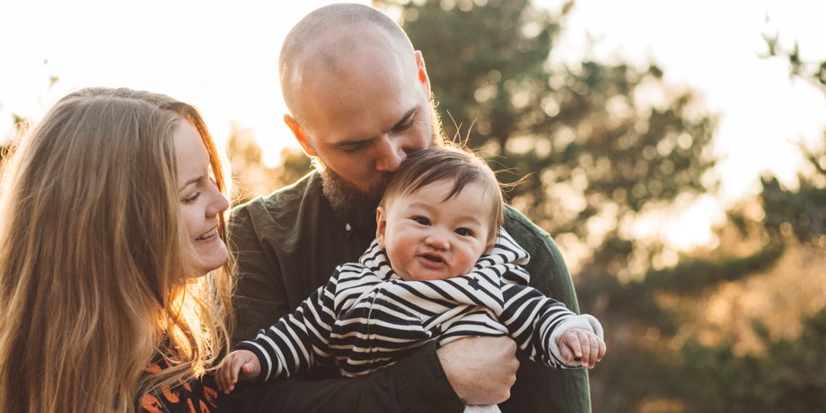 Mammap och pappa håller sitt barn i famnen.