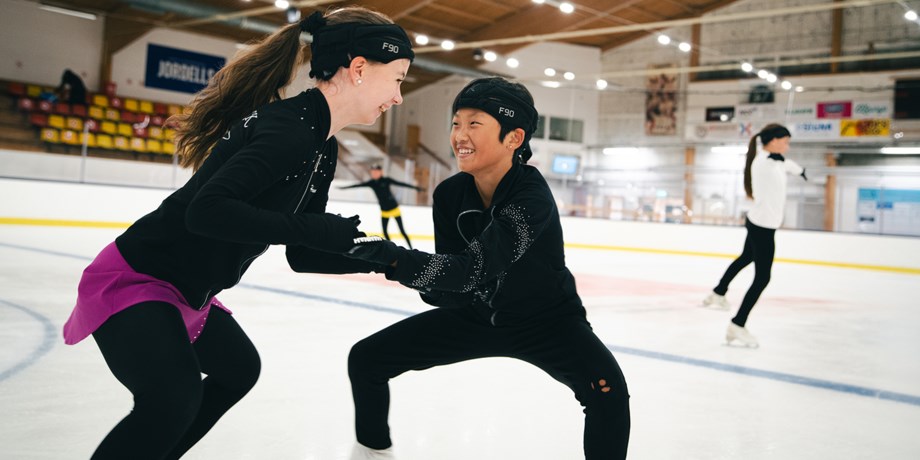 Foto av unga konståkare som tränar i en ishall.