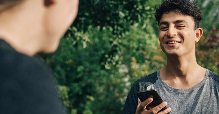 Två unga män står och pratar med varandra i en park.