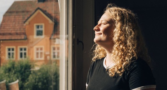 kvinna som blickar ut genom fönstret.