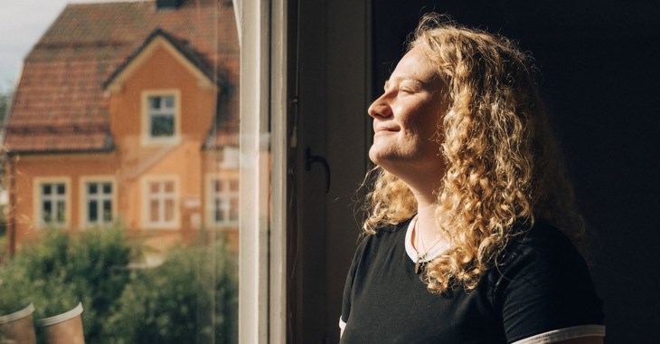 Bild på person som tittar ut genom fönstret.
