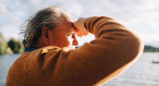 Äldre man tittar ner på solnedgången och hoppas räntorna ska gå upp, bild.