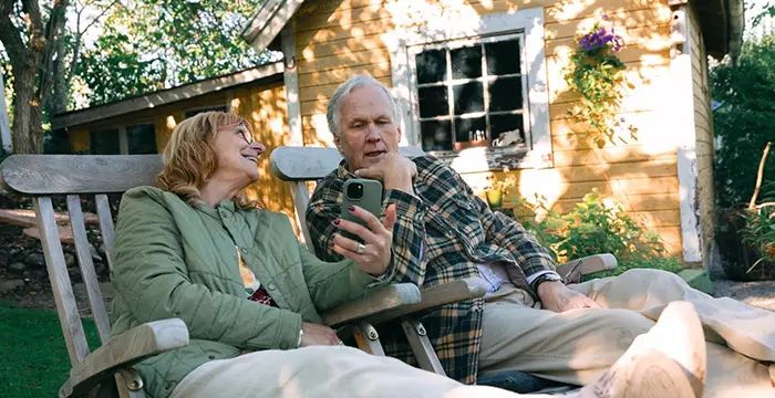 Par i 50-årsåldern sitter i trädgården till sitt fritidshus.