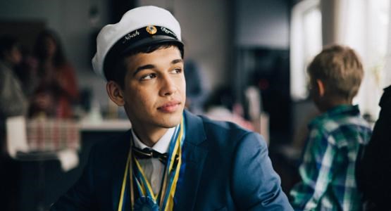 Närbild på ung kille med fundersam min, i som precis tagit studenten.