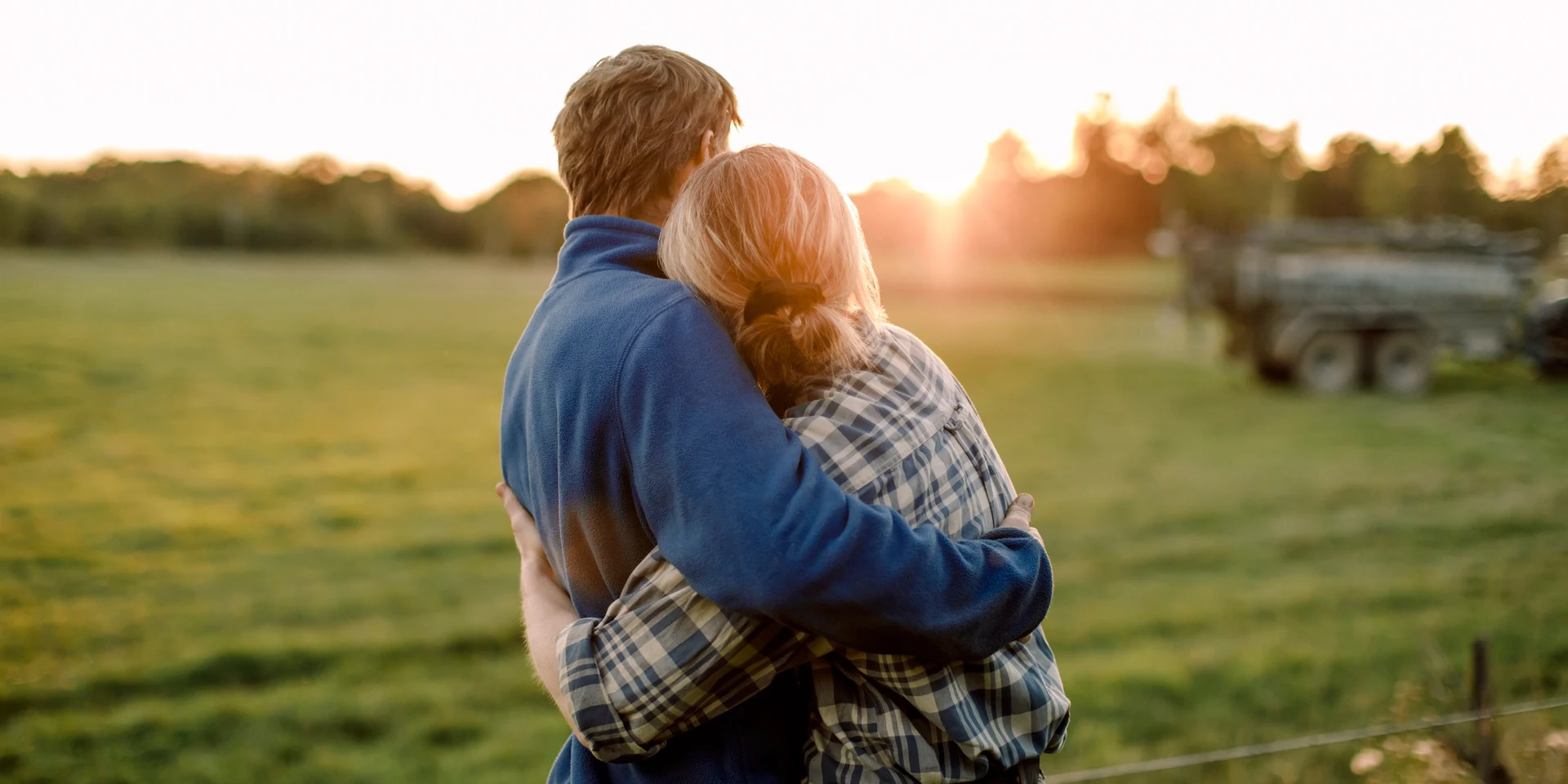 Par kramas på soldränkt fält, fotografi.