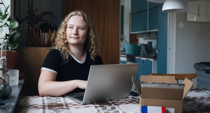 Foto på ung kvinna som sitter vid datorn och ska börja spara i fonder.