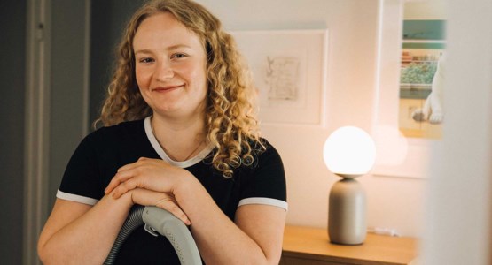 Kvinna med dammsugare tittar in i kameran