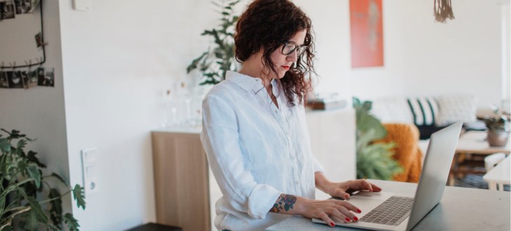 Kvinna stående vid bärbar dator