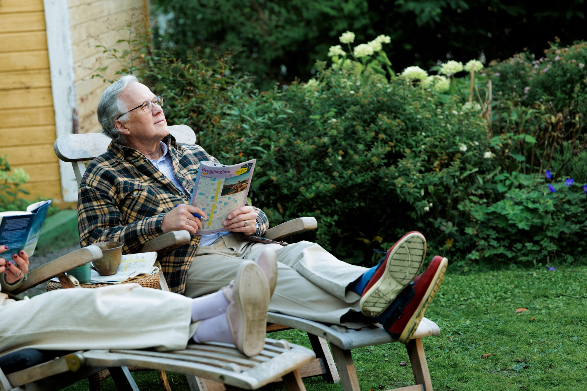Äldre man sitter ute med en tidning i handen 