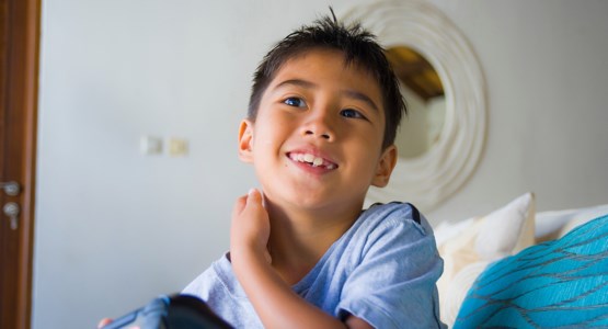 Glad pojke sitter i soffa.