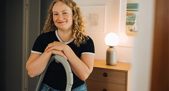 En tjej står lutad över dammsugaren.