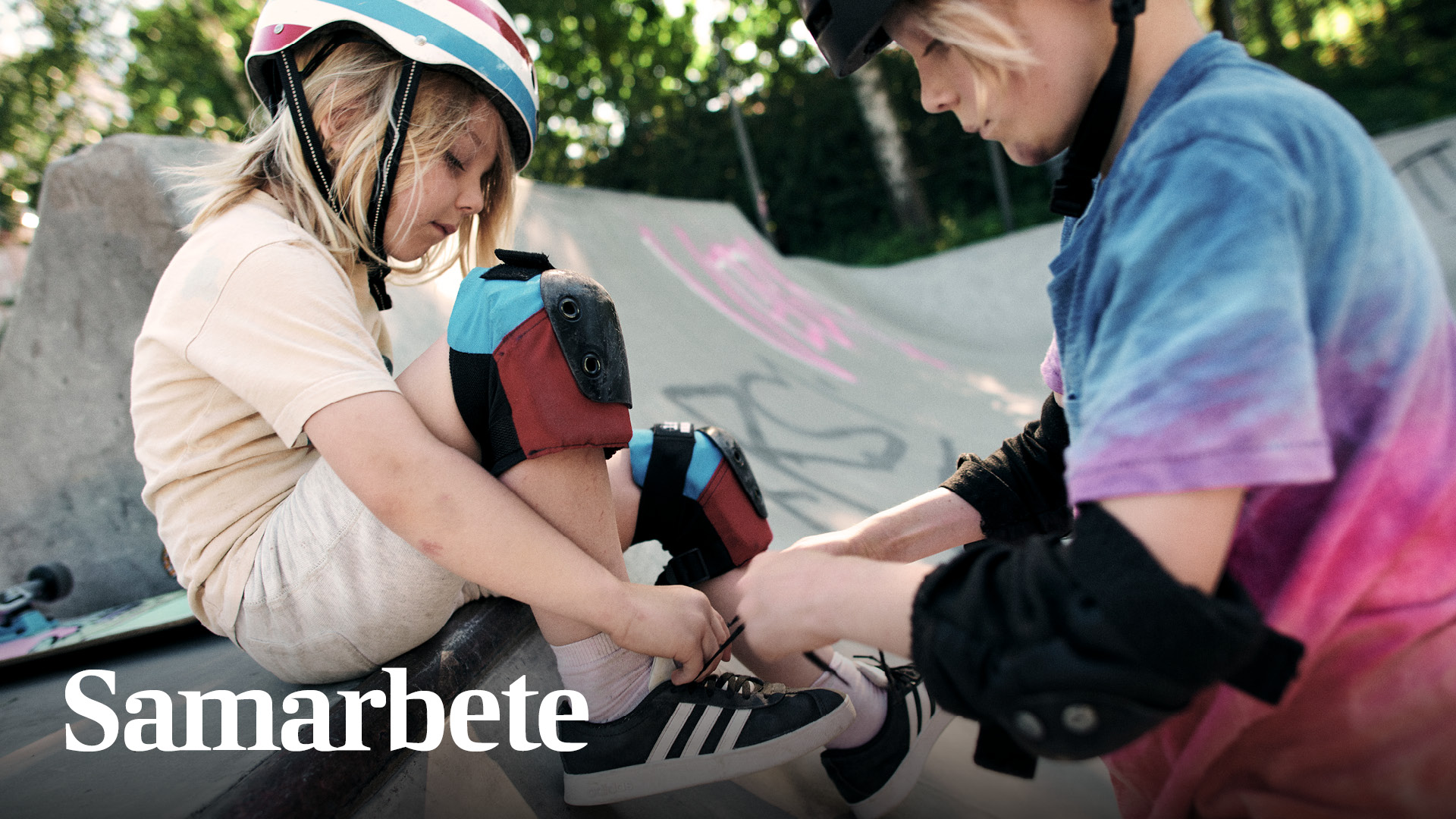 Ett barn hjälper ett annat barn knyta skorna och Samarbete står skrivet intill barnen.