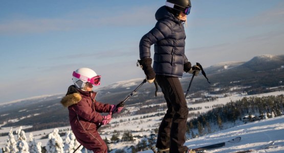 Kvinna och barn i skidbacken