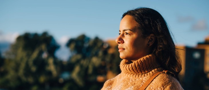 En kvinna blickar ut mot en blå himmel.