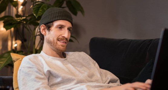 Ung kille sitter med laptop, foto.