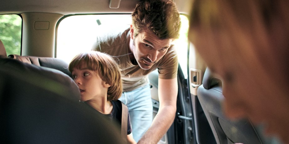 Pappa spänner fast barn i baksätet, foto.