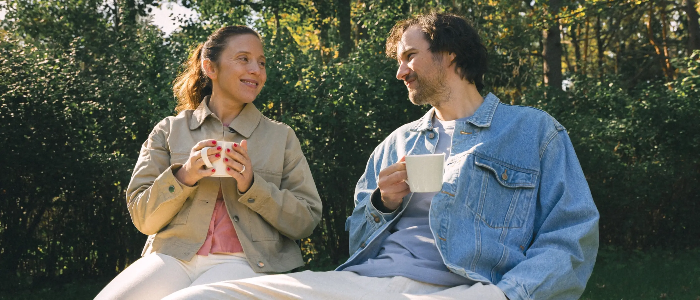 Två personer dricker kaffe i en trädgård.