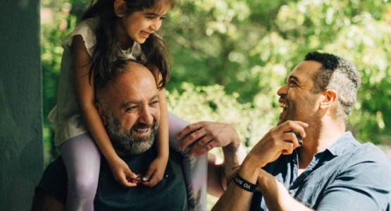 Två män och barn som sitter på axlar
