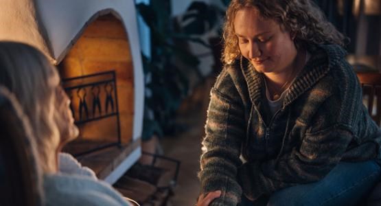 Tvår kvinnor sitter framför en öppen spis 