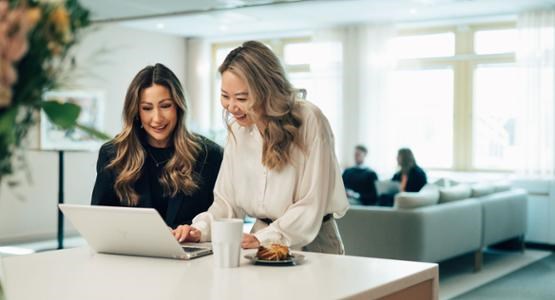 Två kvinnor kollar in i en dataskärm. 