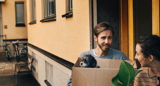 Par bär in flyttlådor i lägenhetshus