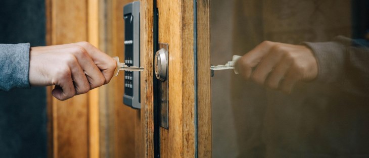 Man låser upp ytterdörr med nyckel