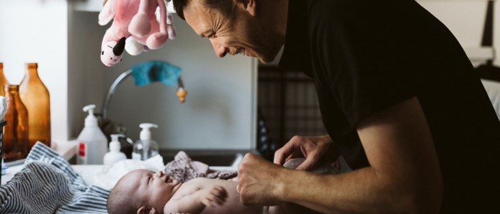 Pappa byter blöja på bebis.