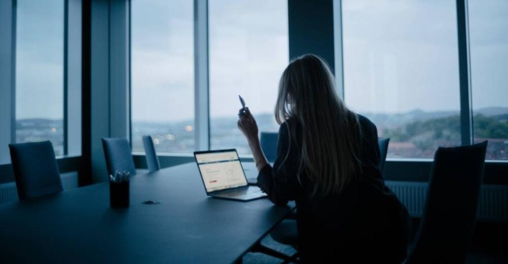 Foto på en kvinna som läser på om ränterabatt vid en laptop i ett höghus med utsikt.