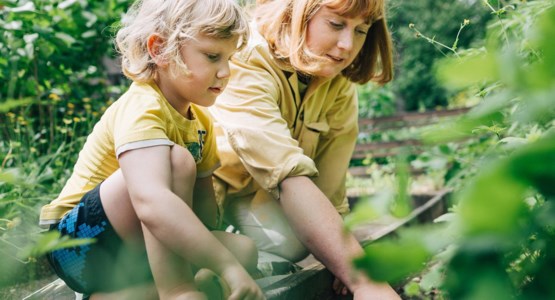 Mamma och liten pojke planterar i rabatt.