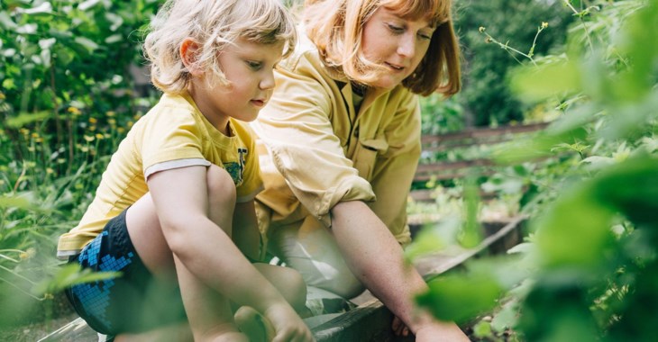 Liten pojke planterar i rabatt tillsammans med sin mamma.
