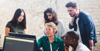 Foto av fem kollegor vid en dator.