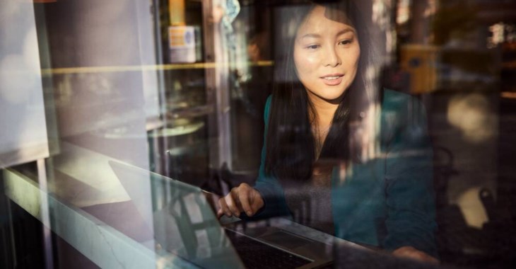 Kvinna med laptop sitter på ett fik.