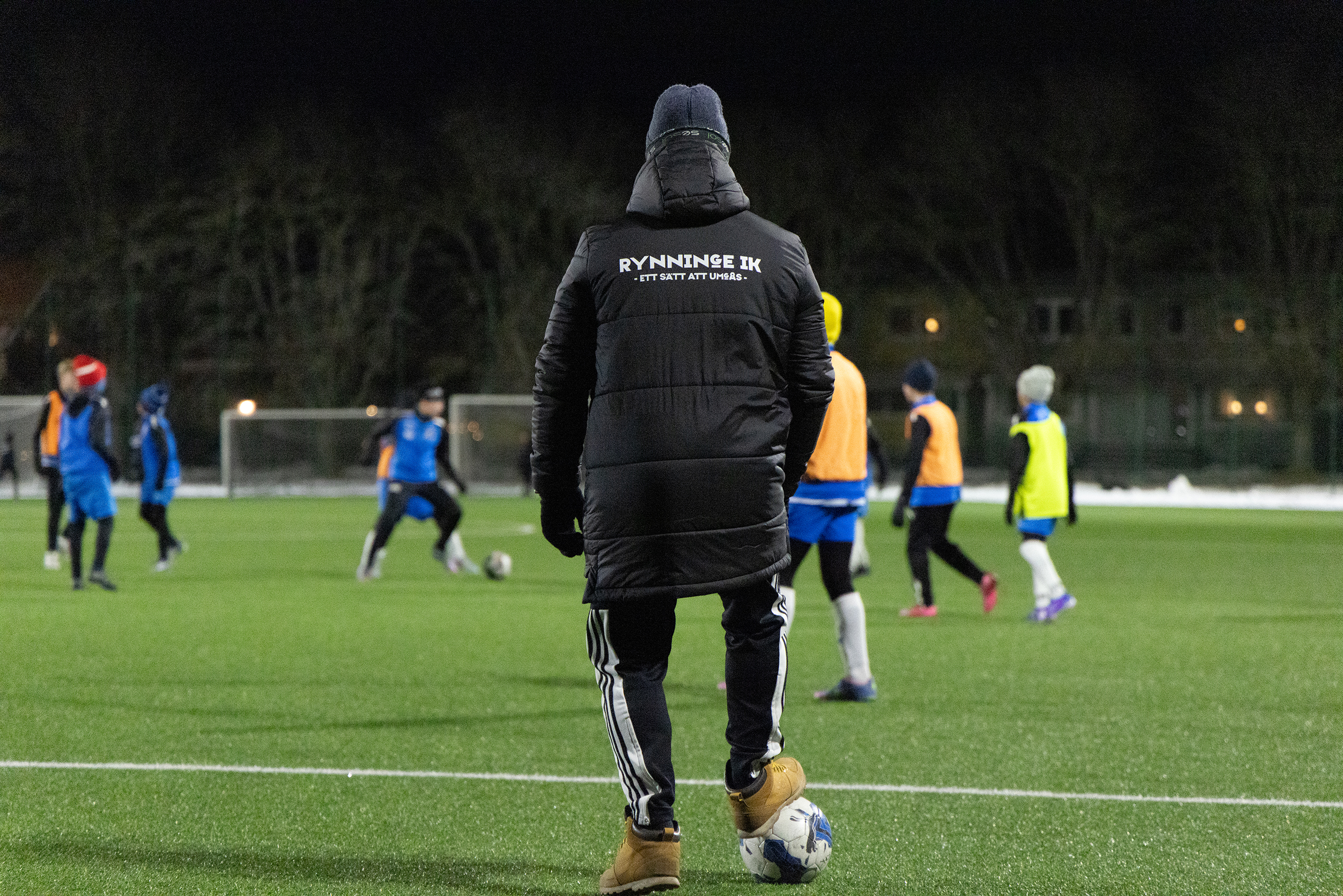 Ryggen på tränare på fotbollsplanen.