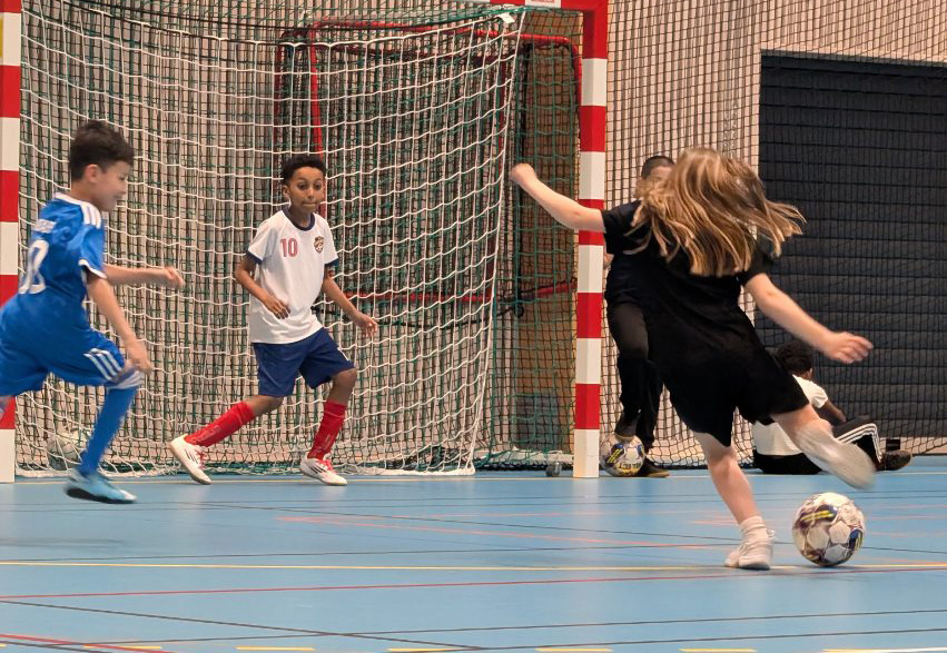 Barn spelar fotboll.