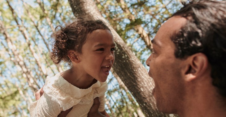 Flicka busar med pappa i skogen.