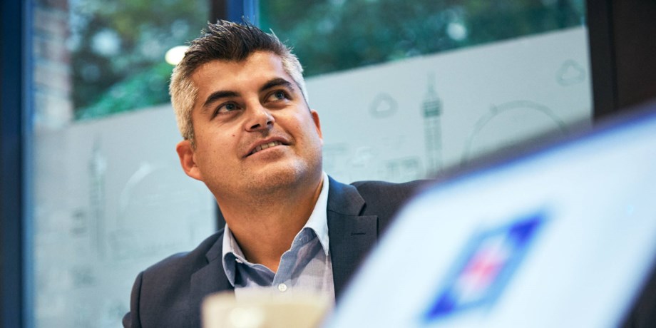 Leende man sitter vid dator. 