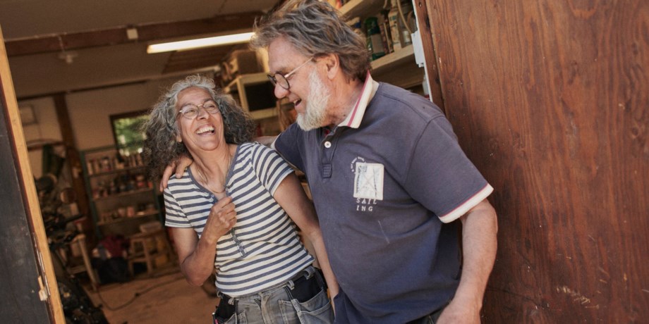 Ett äldre par står i en ladugårdsdörr och skrattar.