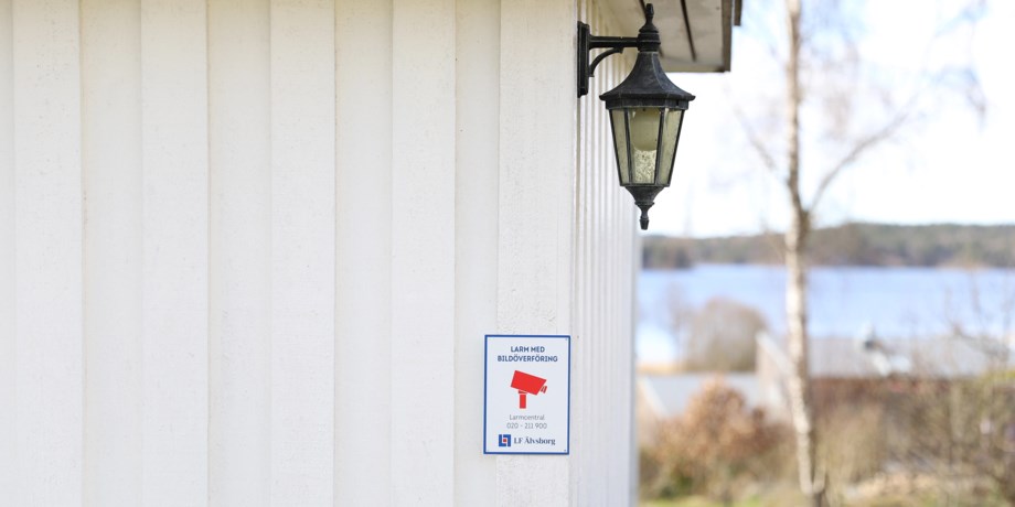 Larmskylt på husvägg.