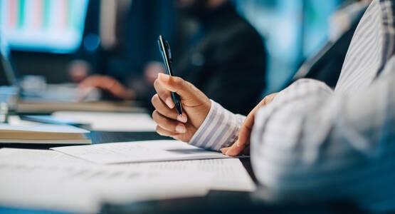 Hand som håller en penna ovanför ett kontrakt om bolån.