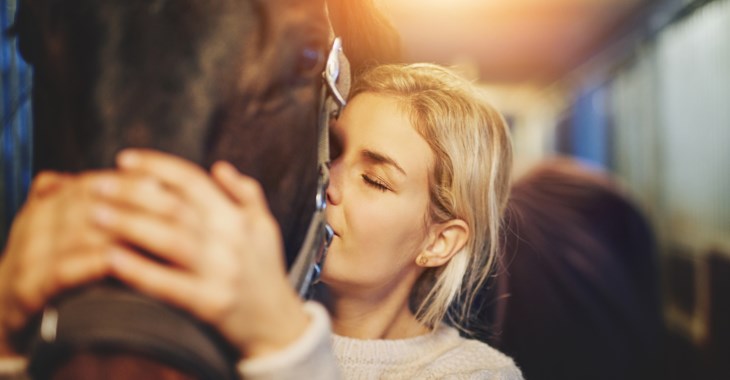 Tjej som kramar om mulen på en häst.